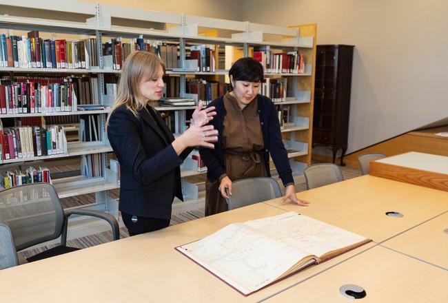 Two SLIS students standing at a table discussing an archival document