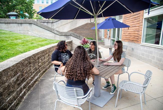 Students sitting in outside patio on main Simmons quad