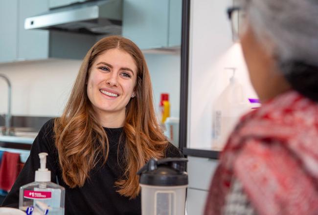 A nutrition student smiling while interacting with another student