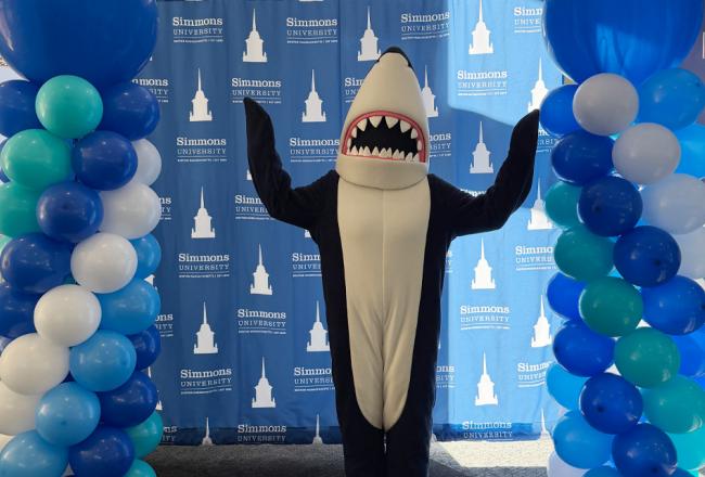 Stormy hanging out at a Simmons event in front of a selfie spot with a Simmons background and surrounded by balloons.