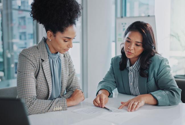 Two women seated at a desk reviewing a paper