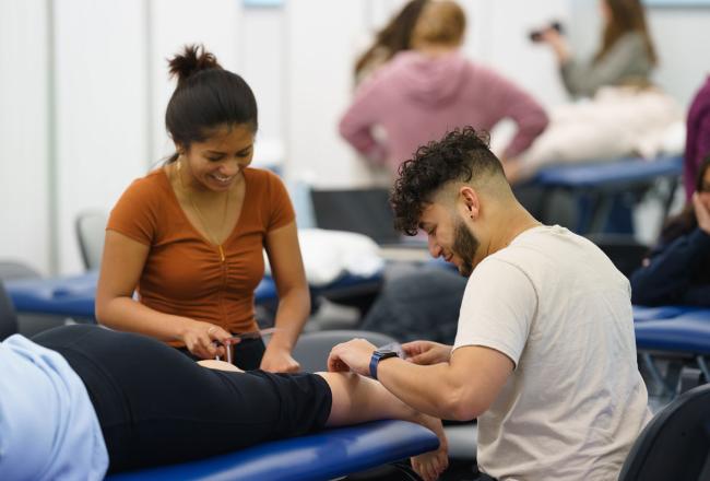 Two graduate physical therapy students working in the PT lab