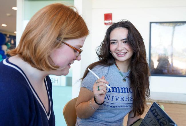 Two Simmons students sitting at a desk having a meeting