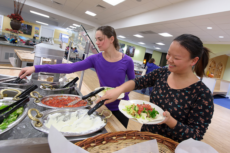 Students preparing plates at a taco bar in the dining hall