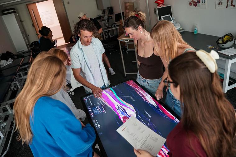 A group of Simmons students gathered around an anatomage table.