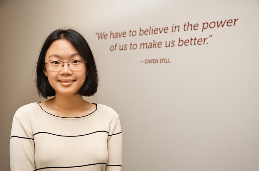 Anna Zhang standing in front of Gwen Ifill quote: "We have to believe in the power of us to make us better."