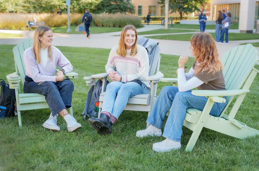 Sydney Iannantuono sitting with friends on the Simmons University quad