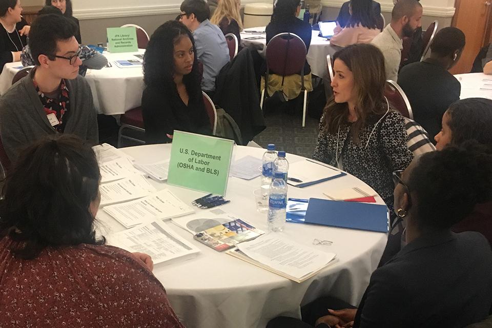 Attendees of government career forum sitting at a table having a discussion.