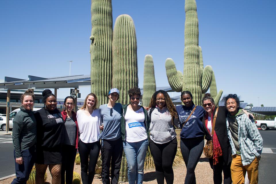 A group of Simmons public health students in front of some tall cacti
