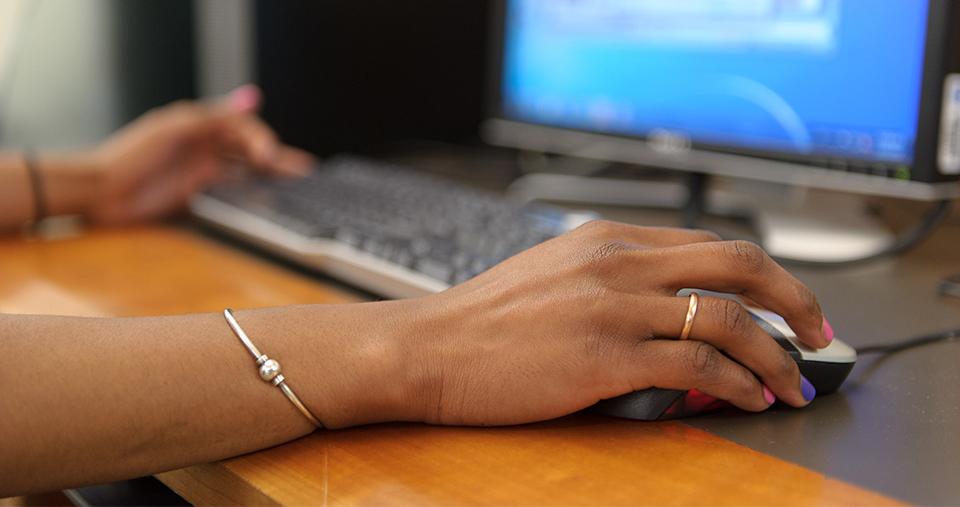Hand using mouse at a computer. 