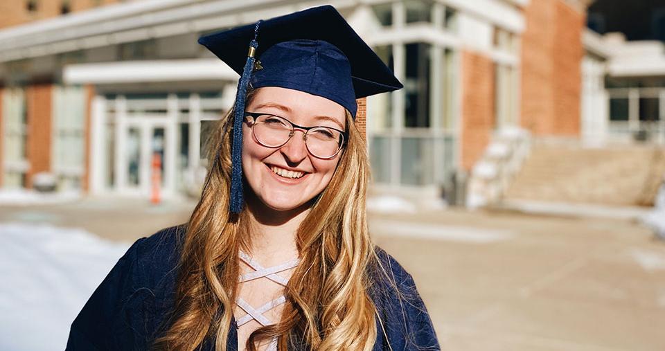 Student on campus in graduation robes