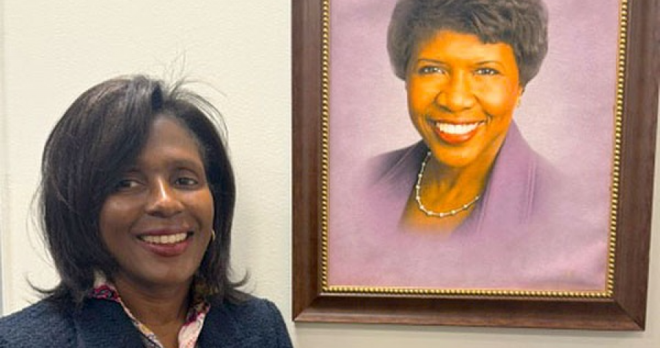 Simmons President Lynn Perry Wooten standing near a portrait of Gwen Ifill