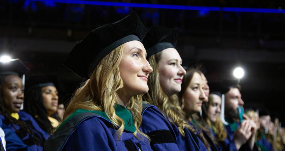 Two rows of graduate students smiling during their Commencement from Simmons University