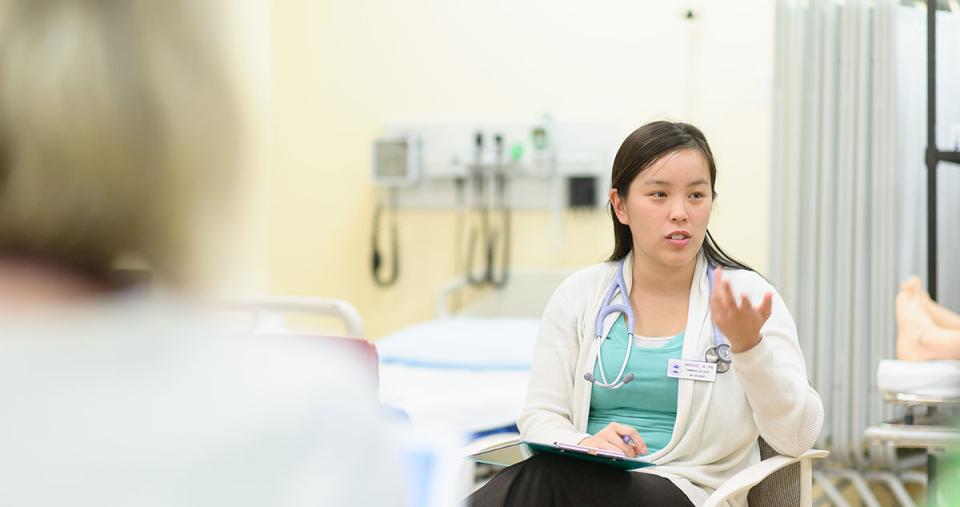 A nursing student seated in a chair and gesturing with her hand