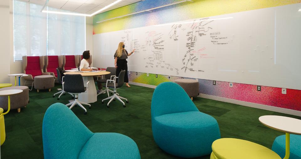 Two people working on whiteboard in room
