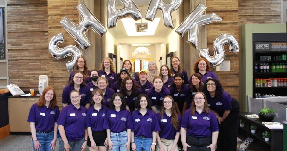 A group of 2025 orientation leaders posing in front of balloons that spell out SHARKS
