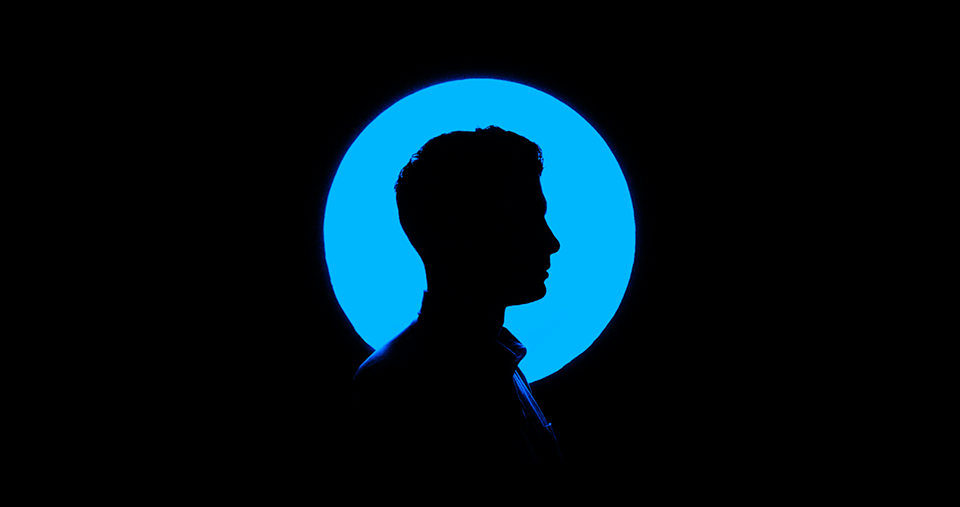 silhouette of person in front of blue circle on a black background