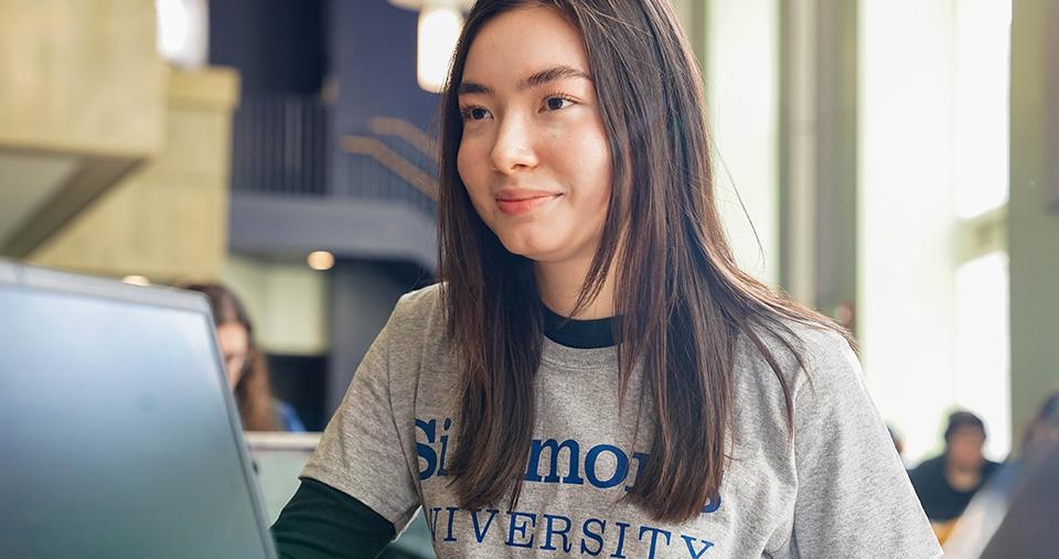 Student is Simmons t-shirt sitting at computer