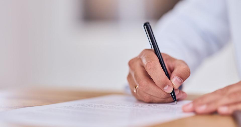 Someone signing a document with a pen