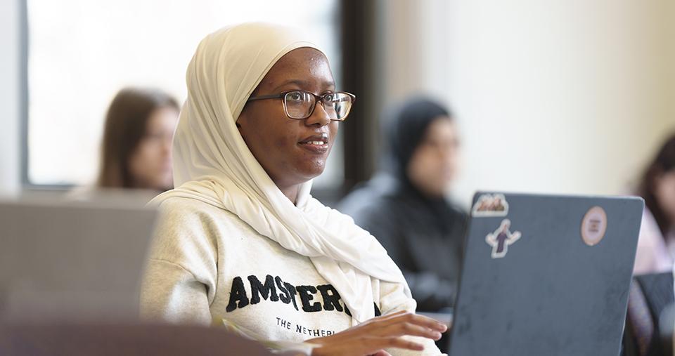 Student sitting in classroom in front of laptop.