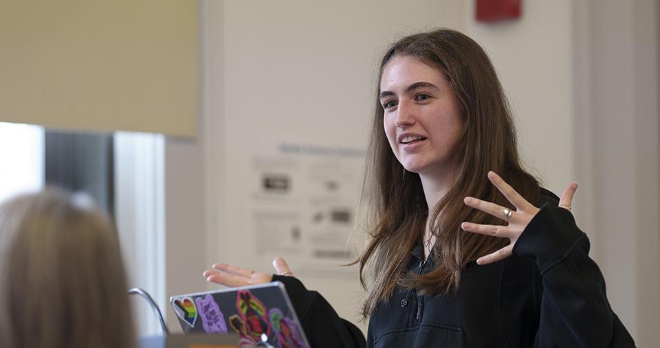 Student standing and speaking in front of class.