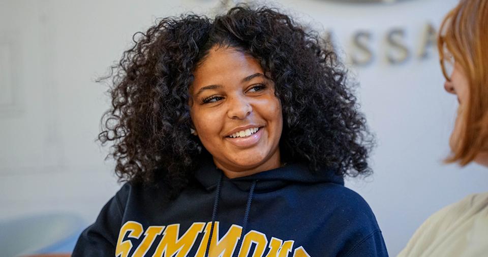 Simmons student smiling talking to another student