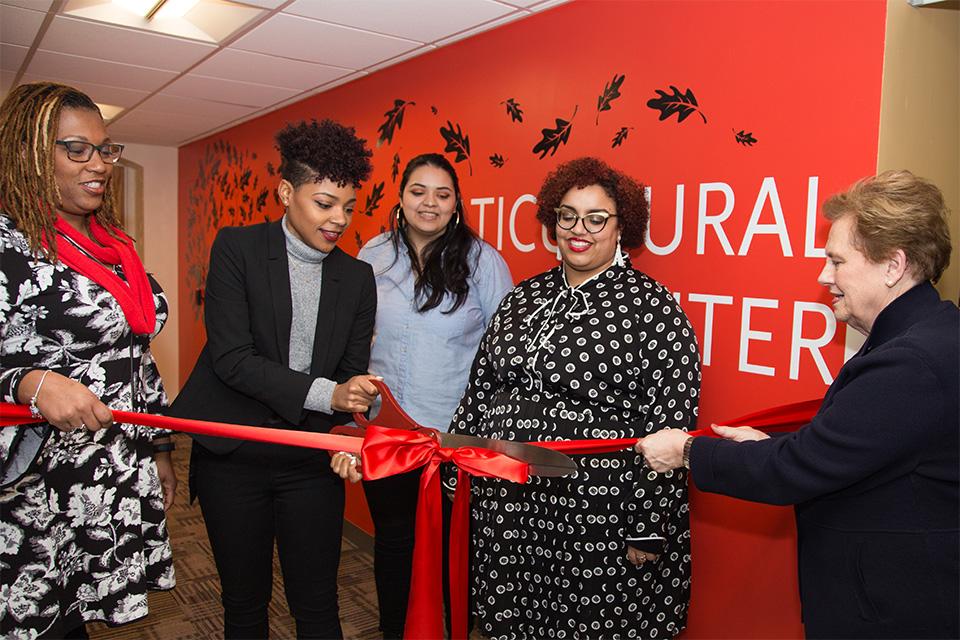 Lisa Smith-McQueenie and Helen Drinan hold ribbon as Nasyria Taylor cuts it to open the Multicultural Center